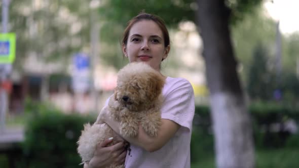 Woman with Toy Poodle Walking in a Park