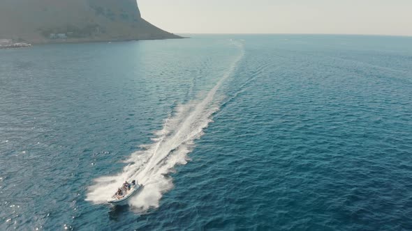 Speedboat with Unrecognized Tourists Rushes Across the Ocean. In the Background Is a Cliff