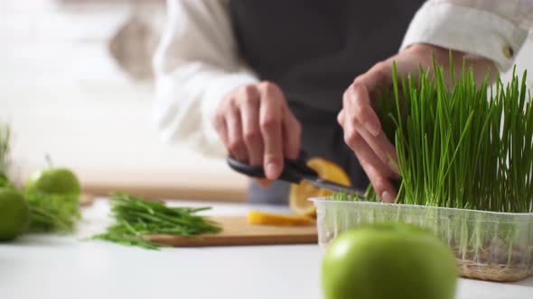 The Process Of Making Smoothies. Cooking Green Spring Smoothie. The Hostess Cuts Fresh Wheat Sprouts