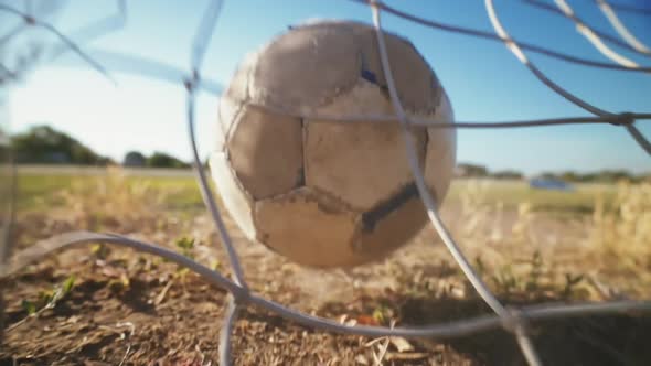 The football player scores the ball into the goal. The boy kicks the ball