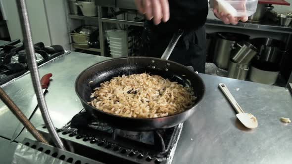 Chef is Making Flambe Sauce on Restaurant Kitchen with Onion and Wine
