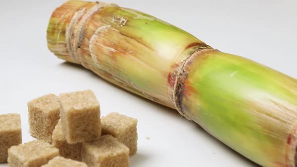  Heap of cane sugar, sugar cubes and sugar cane on white background