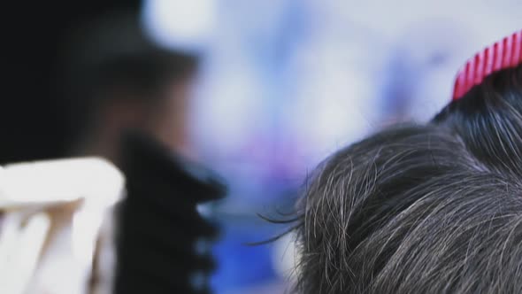 hairdresser does trendy haircut to young customer in salon