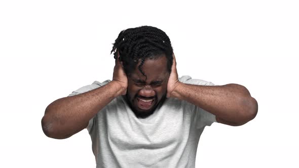 Portrait of Confused Dark Skinned Guy with Afro Pigtails Grabbing His Head or Covering Ears While