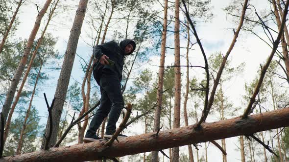 a Man Balances on a Fallen Tree and Looks for a Cellular Signal