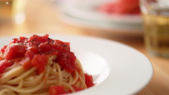 Camera follows shredding parmesan cheese over fresh tomato sauce spaghetti in plate. Slow Motion.