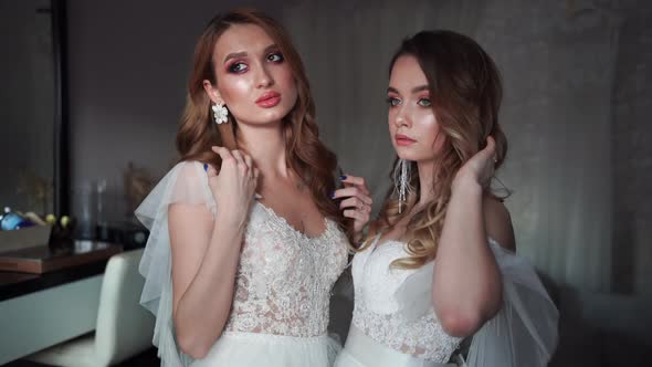 Two Young Models Posing in Front of the Photographer in a Wedding Dress.