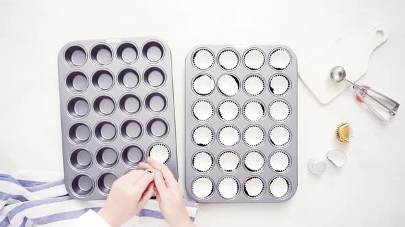 Flat lay. Lining cupcake pan with paper cupcake liners.