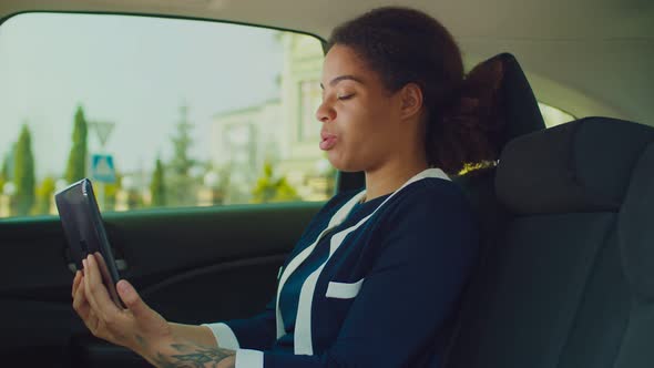 Businesswoman in Car Video Conferencing on Tablet Pc