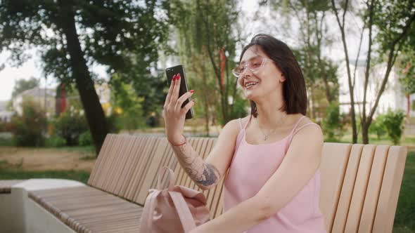 Young happy Asian woman outdoor smiling and laughing using mobile phone for video chat online.