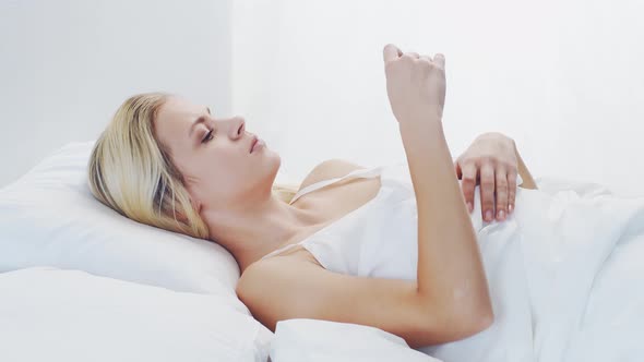 Young woman lying in the bed. Beautiful blond sleeping girl. Morning in the bedroom.