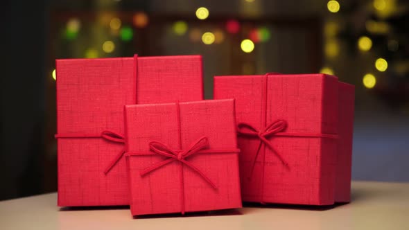 Closeup of Red Gift Boxes in a Row with Bows on Colorful Christmas Lights Background