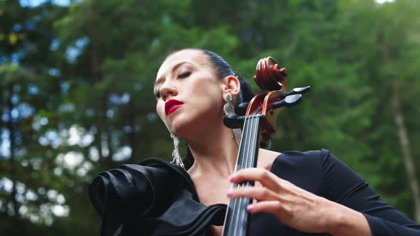 Passionate woman performs music. Attractive woman is playing the cello and enjoys the music