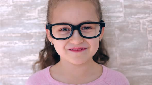 Portrait of a Cute Girl, Happy Child Looking at the Camera Smiling. Little Girl in Black Glasses