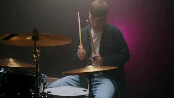 Drummer Playing the Drum Set in a Dark Room on a Black Background