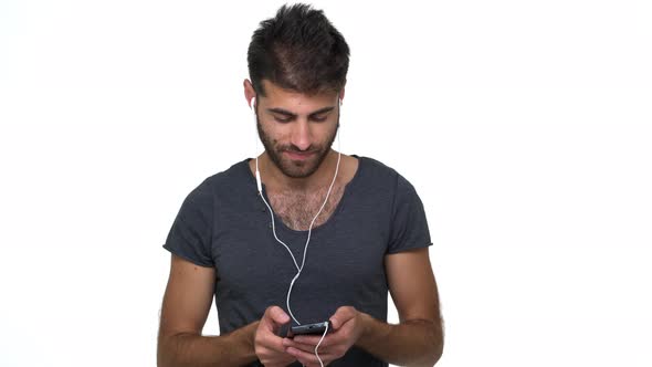 Caucasian Thin Male Model Posing Over White Background Listening Music Using Cellphone and