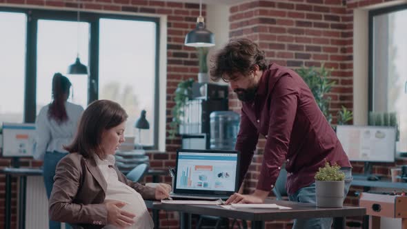 Business Woman Expecting Child and Having Discussion with Man While Working