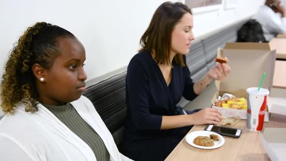 African American woman laughs at joke while eating lunch with Caucasian friend