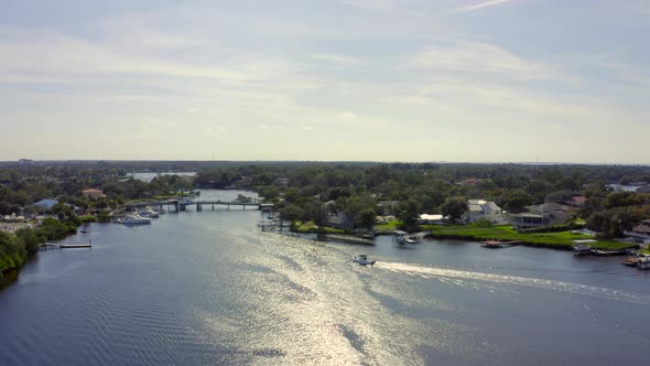 Slow Forward Aerial Pan of a Speed Boat on Bay by Waterfront Houses in Florida