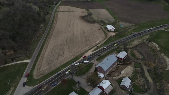 Over view of traffic accident on rural highway in front of farm buildings on a rainy day.