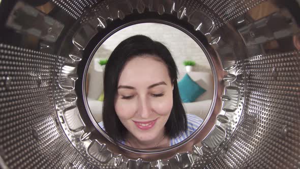 Young Woman Happily Examines the Drum of a Washing Machine