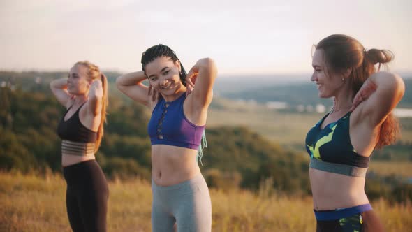 Three Young Women in Sports Clothes Doing Aerobic Exercises