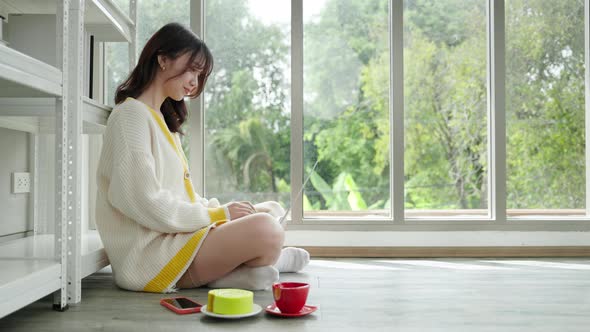 Asian woman working on the floor with laptop in the living room of the house