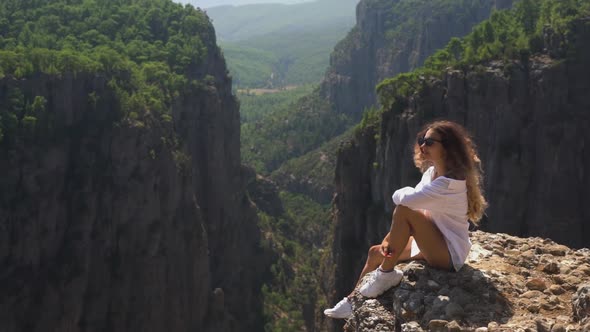 Woman in White Shirt and Sneakers on Rock Against Mountains