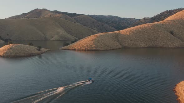 Aerial Drone Tracking Shot of a Boat Towing a Tube on.a Mountain Lake (Lake Kaweah, Visalia, CA)