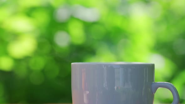 Hot Drink in a Cup Against the Background of a Summer Garden in the Morning