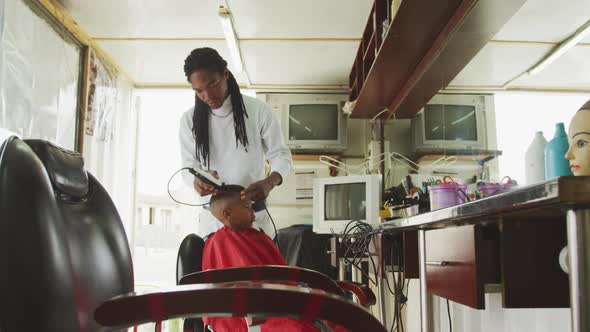 Distant view of African man cutting African boy hair