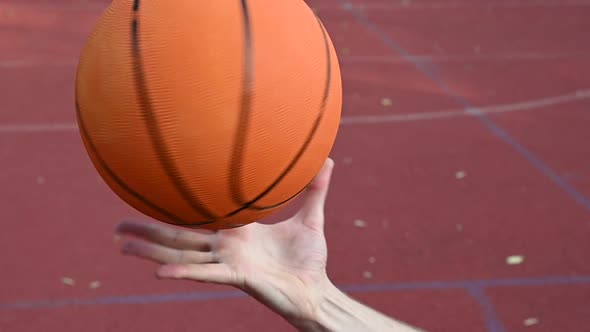 Man spinning basketball ball on hand palm