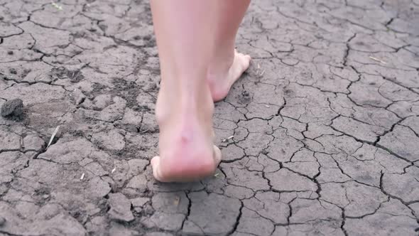 Barefoot Girl Walks on Dry Lake Land Drought Land Cracks No Water