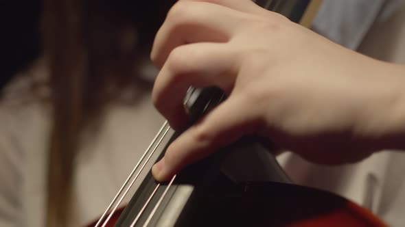 Hand of Female Musician Playing with Bow and Fingers on Strings of Cello at Concert Closeup