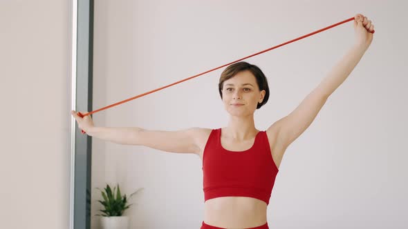 Sporty Woman in Red Costume Doing Exercises with the Fitness Band