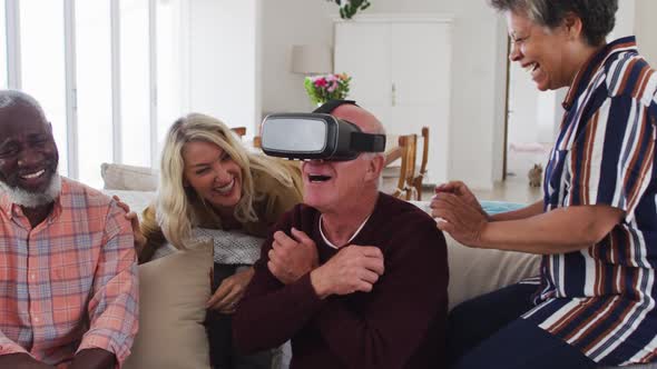 Two diverse senior couples sitting on a couch caucasian man is using vr googles