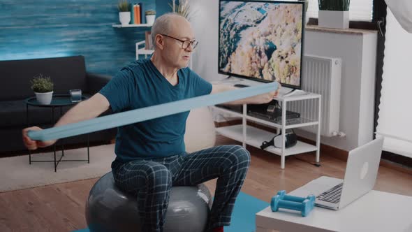 Pensioner Stretching Resistance Band to Work Arms Muscles