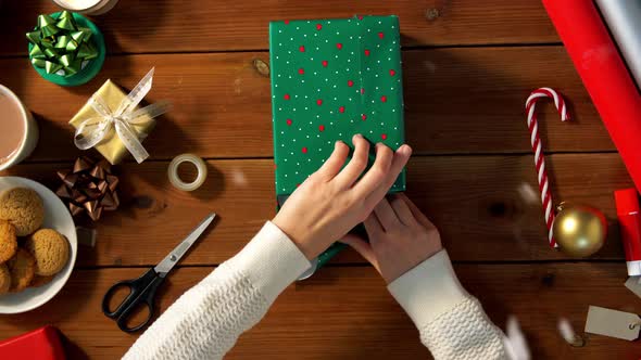 Woman Wrapping Christmas Gift Into Paper at Home