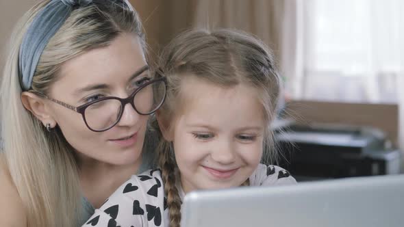 Mom and daughter play a game on the computer, break, rest from lessons