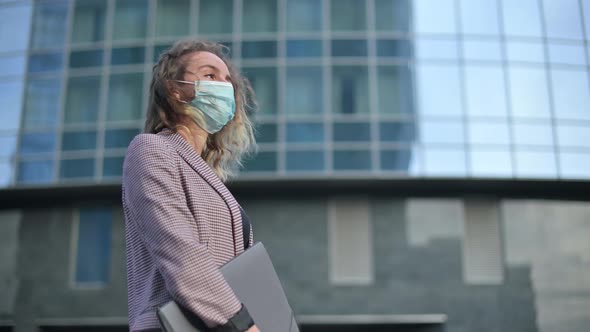 Young woman in a medical mask stands against the background of a business center