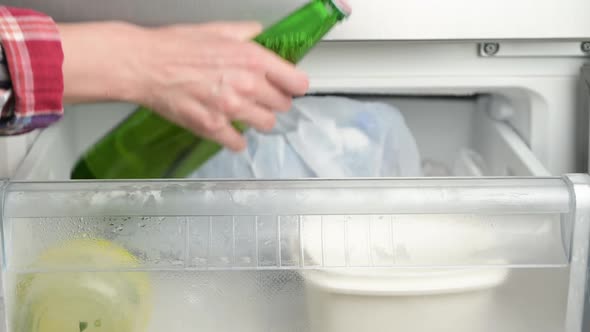 A woman takes a chilled bottle of beer from the freezer in the summer heat