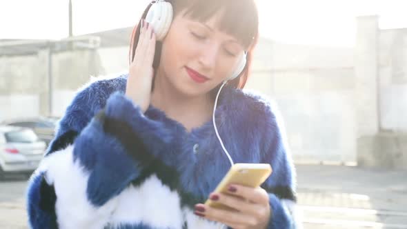 Young beautiful eastern woman listening music with headphones and smart phone