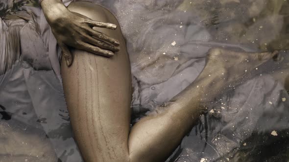 Slender Female Leg Covered Gold Dye in Water Woman Is Stroking Her Body