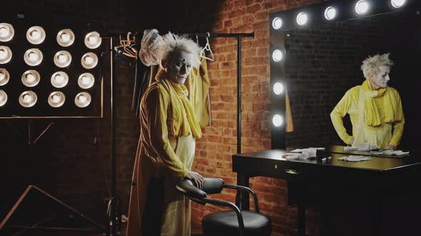 Sad Mature Actor in Yellow Costume Stands in Dressing Room