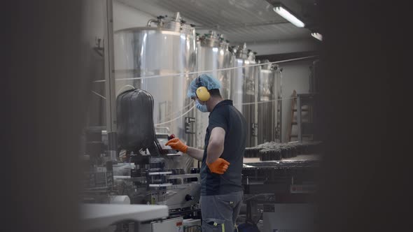 Male Worker In Mask Operating Beer Production Equipment During Working Process  Medium