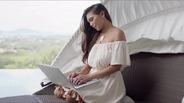 Relaxed Woman Using Laptop on Terrace Against Beautiful Landscape