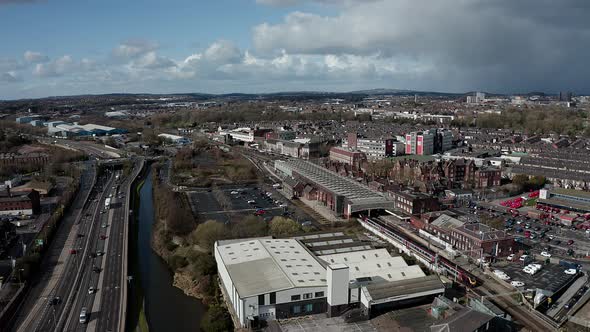 Aerial footage of trains approaching Stoke on Trent train station in the midlands by the canal, wate