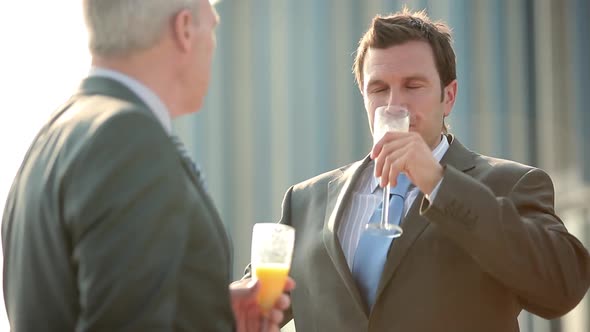 Businessmen talking and toasting with bucks fizz