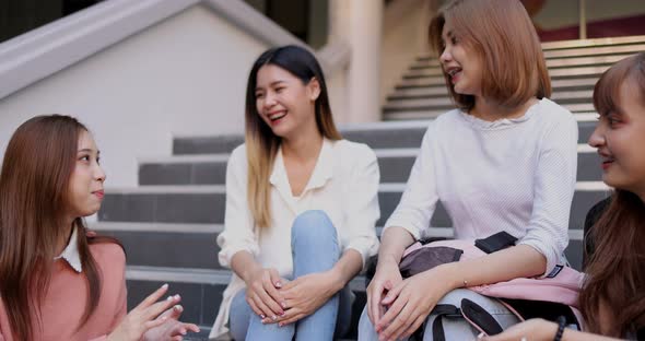 Group of Asian girl friends meeting and talking on stairway front of the building.