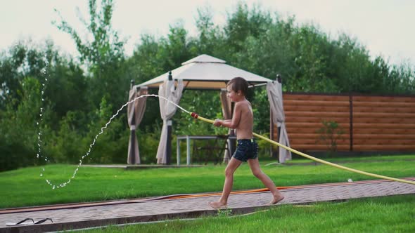 The Two Boys Are Playing with Mom and Dad in the Backyard of Their House Drenching with Hose